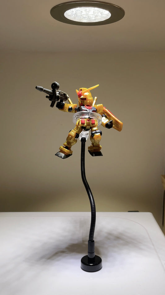 Mobile Suit Ensemble Gundam on a magnetic stand attached to the top of a microwave under a spotlight